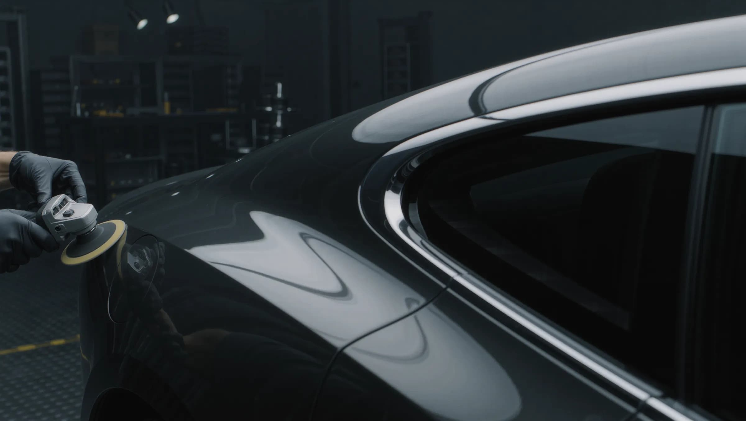 Close view of a polisher pad on a gleaming dark panel beside a chrome window line.
